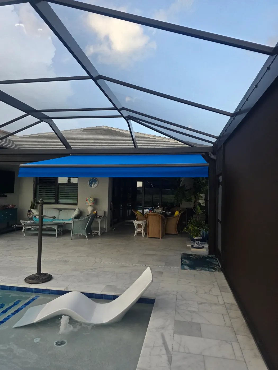 Blue retractable awning extended over a poolside patio